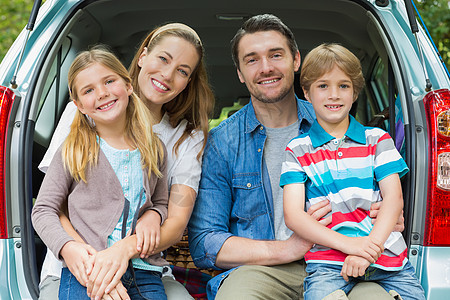 坐在车厢里的四人家庭幸福的肖像微笑树木树干父亲喜悦女儿姐姐男人闲暇儿子图片