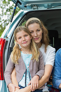 坐在汽车后备箱里的母亲和女儿微笑假期运输女性团结农村幸福郊游女士童年家庭图片