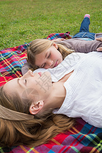 轻松的母亲和女儿躺在公园里闲暇女孩毯子野餐眼睛女性农村说谎花园团结图片