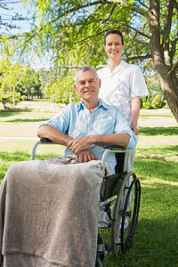 女人与她父亲坐在轮椅上 在公园退休功能截瘫闲暇草地夫妻人员疾病女性男人图片