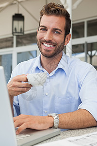 快乐的青年商务人士 在笔记本电脑饮用水咖啡中工作露台桌子男性技术闲暇杯子咖啡店人士商务衬衫图片