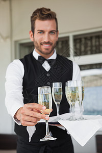 提供香槟长笛的英俊服务员图片