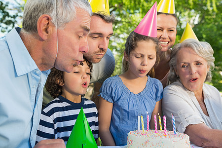 盛大家庭在派对帽子 吹生日蛋糕男性桌子兄弟姐妹妈妈生日爸爸女性庆典父母蜡烛图片