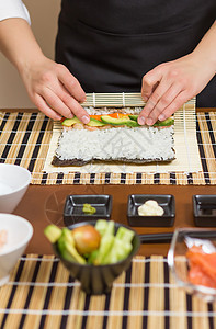女厨师的手卷起日本寿司海鲜美食竹子女孩黄瓜餐厅床单饮食女士鱼片图片