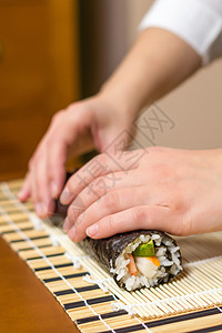 女厨师的手卷起日本寿司黄瓜竹子女性鱼片女士午餐饮食大豆海藻食物图片