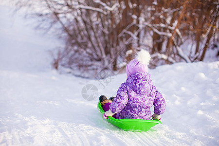 可爱的小可爱女孩在温暖的冬日拉着雪橇外套快乐婴儿喜悦森林衣服季节幸福微笑公园图片