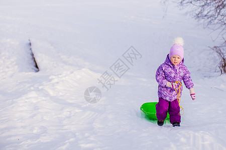 小女孩在温暖的冬日拉起雪橇帽子女儿衣服森林草地微笑幸福婴儿季节快乐图片