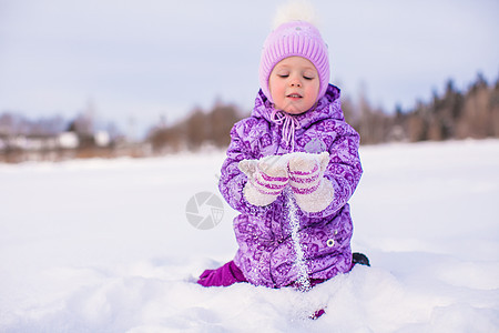 快乐的小女孩在寒冬阳光明日玩雪女儿幸福女孩闲暇享受乐趣紫色草地雪花婴儿图片