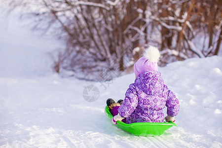 可爱的小可爱女孩在温暖的冬日拉着雪橇雪花快乐草地帽子公园婴儿喜悦乐趣季节森林图片