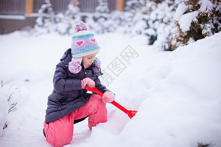 小女孩在冬天天玩雪铲雪的游戏晴天幸福季节女性雪堆雪花童年婴儿孩子闲暇图片