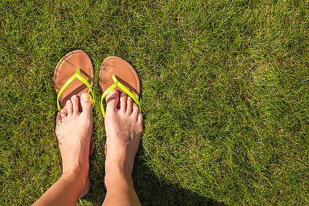 在绿草上用拖鞋紧紧女人的腿鞋类字拖装饰品旅行配饰脚步圆形衣服热带阳光图片