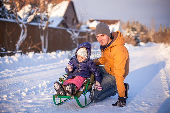 年轻老爸在阳光明媚的冬天天 骑着可爱的小女儿滑雪女孩快乐闲暇微笑男人雪橇乐趣幸福喜悦成人图片