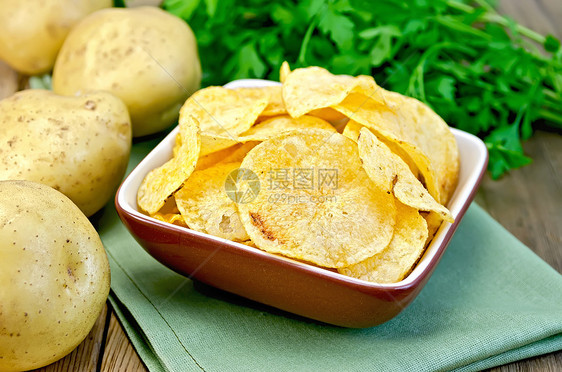 碗里的薯片和一块土豆 在板上和餐巾纸上图片