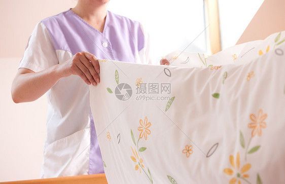 妇女做床铺枕头女佣卫生房间床单家务客房帮助亚麻打扫图片