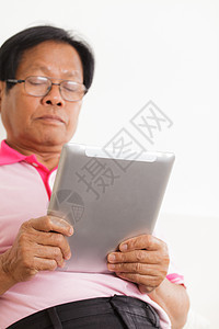 高级男子使用数字平板电脑房子长椅头发沙发技术退休商务男人软垫学习图片