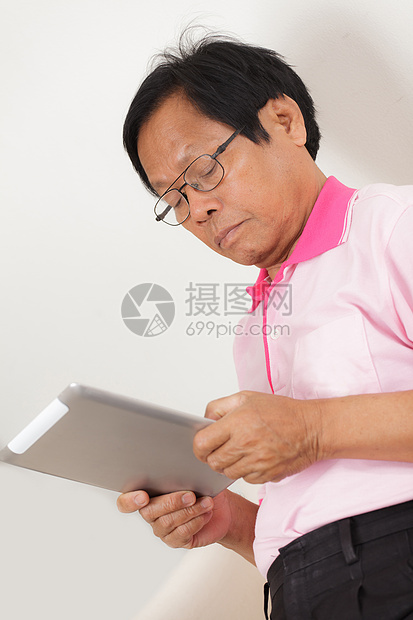 高级男子使用数字平板电脑男性学习男人电子老年人退休沙发软垫成人商务图片