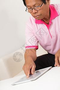高级男子使用数字平板电脑人士成人退休男人灰色软垫学习房子电子商务图片