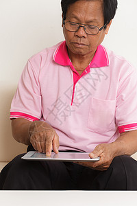 高级男子使用数字平板电脑互联网成人人士学习长椅房子男性沙发老年人男人图片