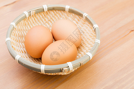 配木制背景的篮子鸡蛋图片