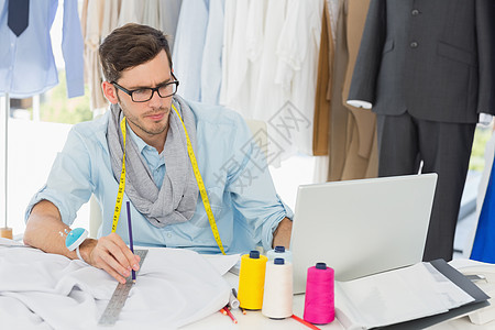 男性时装设计师在设计自己的设计电脑草图裁缝工作室笔记本卷尺工作造型师工艺创造力图片
