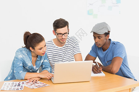 三名集中的青年艺术家在笔记本电脑上工作图片