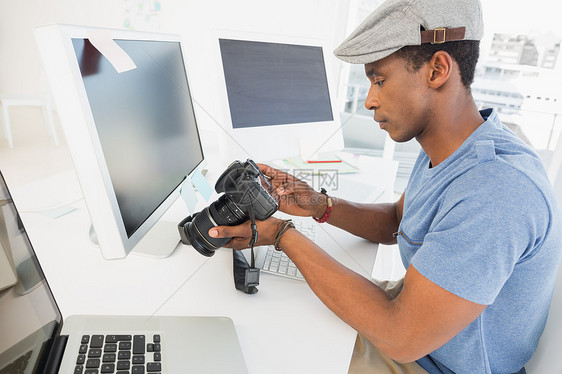 照片编辑在办公室看数码相机的照片编辑电子创造力男人工作公司机构屏幕男性商业摄影师图片