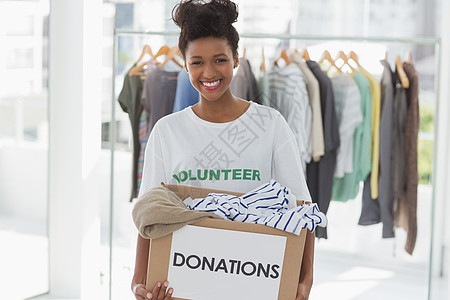 向年轻微笑的少女献衣服服务收集社区服务盒子衣架志愿者机构社区志愿捐赠图片