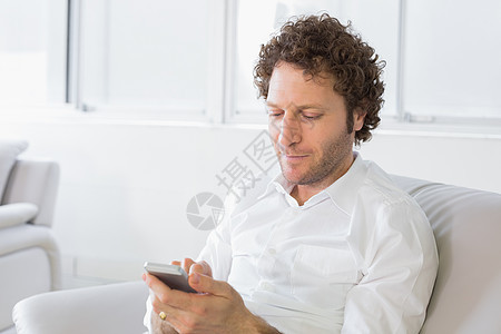 在家放松的男子短信信息电话卷发男性房子长椅棕色男人衬衫客厅闲暇图片