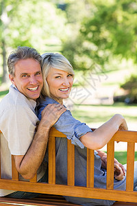 坐在公园长凳上的一对微笑的夫妇图片