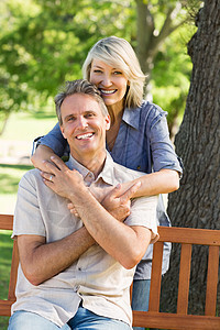 女人从后面的公园里抱男人享受绿地微笑女性亲热闲暇时间长椅男性农村图片