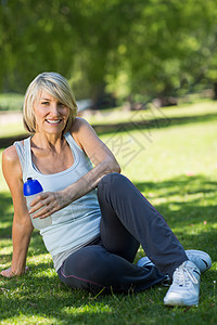 体育妇女把水瓶放在公园时间运动闲暇微笑瓶子绿地农村运动服水壶土地图片