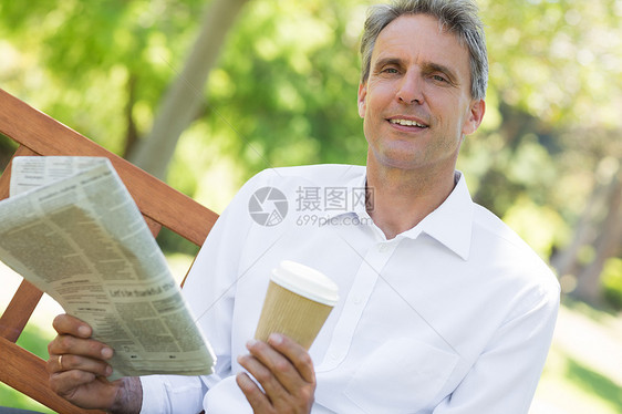 拥有报纸和咖啡杯的商务人士在公园中图片