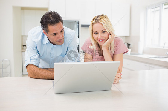 在厨房使用笔记本电脑的一对微笑夫妇房子女士闲暇夫妻男人技术女性家庭生活柜台男性图片