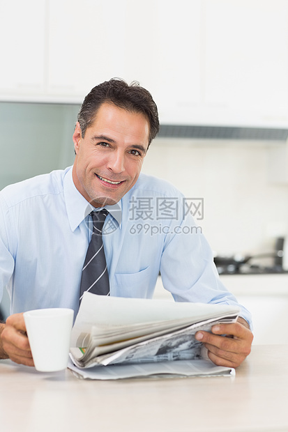 在厨房里用咖啡杯和报纸微笑着身穿盛装的男子家庭生活闲暇柜台男人衬衫咖啡领带杯子阅读饮料图片