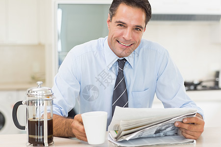 在厨房里用咖啡杯和报纸微笑着身穿盛装的男子男性男人饮料家庭生活咖啡房子阅读柜台杯子衬衫图片