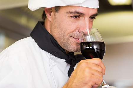 特写一个闻着红酒味的男厨师职业男人帽子男性酒杯玻璃厨房制服酒精工作图片