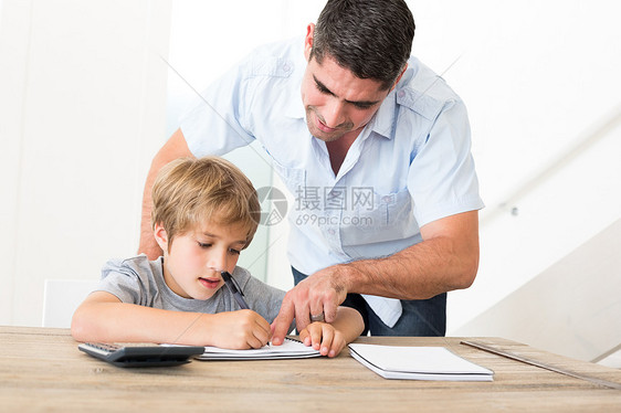 父亲协助儿子做家庭作业男人家庭作业桌子专注教育笔记本写作学习家居知识图片