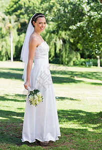 新娘在公园中拿着花束生活婚礼婚纱女性面纱微笑女士开端花园事件图片