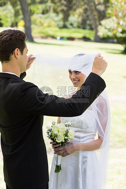 爱新郎的新娘揭开面纱套装丈夫新婚女士婚礼妻子公园微笑起重婚姻图片