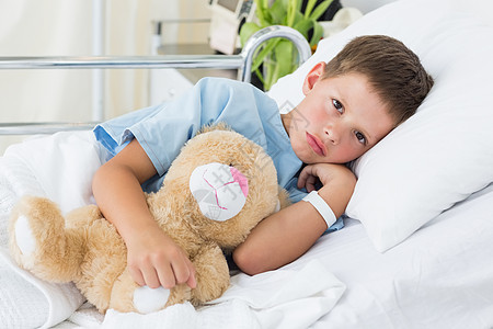 医院里带着泰迪熊的小男孩服务男性枕头男生诊所病房制服疾病病人友谊图片