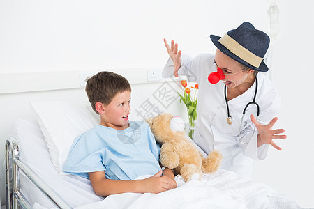 医生穿着小丑服装 在医院招待生病的男孩病人娱乐性玩具疾病从业者手臂照顾治疗保健帽子图片