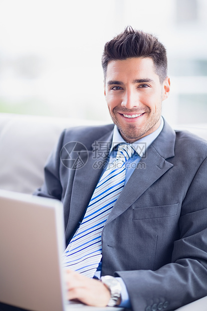坐在沙发上使用笔记本电脑的快乐商务人士图片