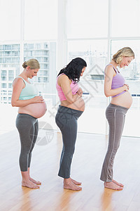 快乐的孕妇站在一排长线上图片