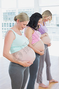 站在一排边上欢笑着微笑着的孕妇们图片
