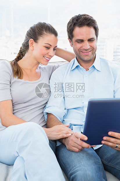 坐在沙发上快乐的情侣使用平板电脑图片