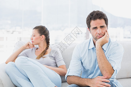 男人在沙发上看着和心烦意乱的女朋友在一起的照相机图片