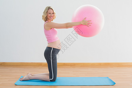 快乐的金金发孕妇举球运动图片