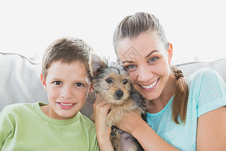 微笑的女人带着她的儿子抱着 她的日新月小狗图片