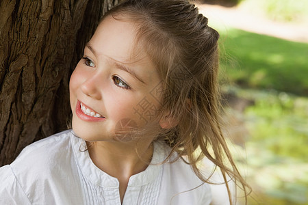 微笑着的年轻女孩在公园里望而却步图片
