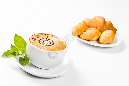 大杯咖啡和盘子上的羊角面包牛奶泡沫薄荷小吃甜点食物桌子香气报纸美食图片